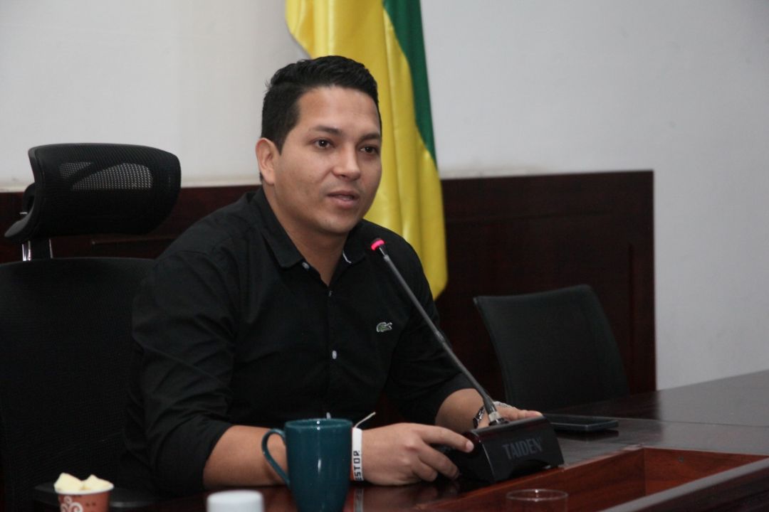 Nestor Ivan Rodriguez sentado. La bandera de colombia junto a el.